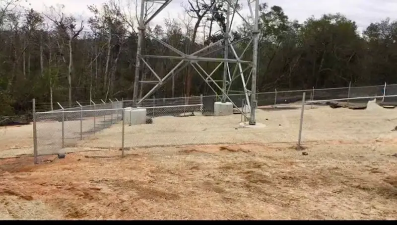 Galvanized chain link fence around a fenced equipment compound on cleared sandy ground, a Southern Line Fence & Finish job