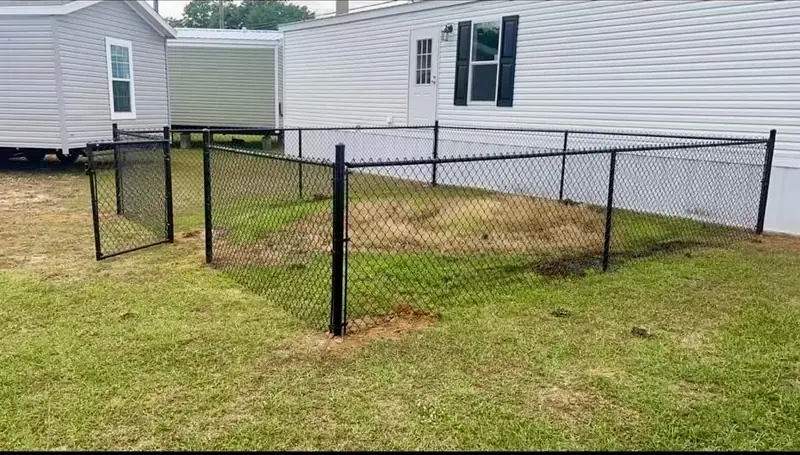 Black chain link fence enclosing the side yard of a home, built by Southern Line Fence & Finish