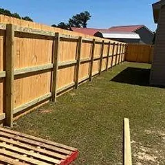 A long new pine privacy fence running down a side yard to a garage
