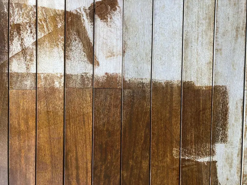 Wood fence boards half stained brown and half bare gray