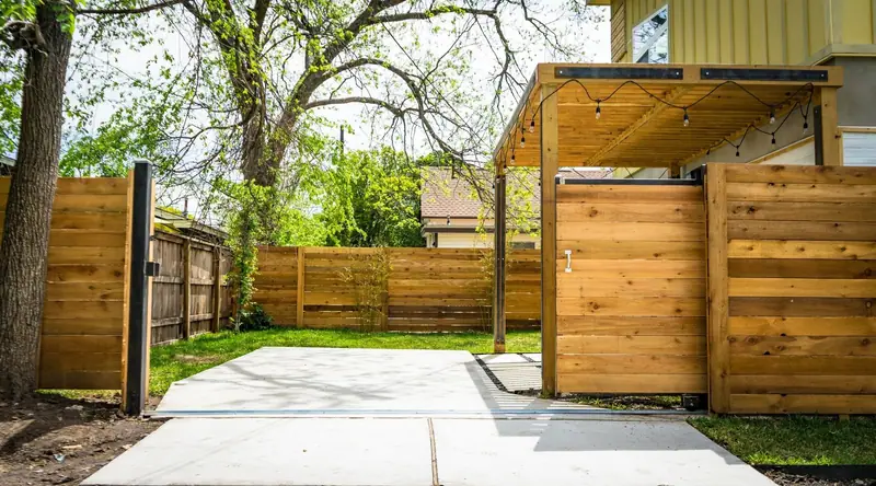 A new horizontal-slat cedar privacy fence and sliding gate around a backyard patio